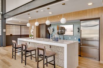 a kitchen with a large island with a sink and a row of chairs in front of it